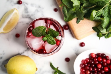 Photo of Tasty refreshing cranberry cocktail and fresh ingredients on white marble table, flat lay