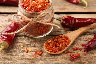 Chili pepper flakes and pods on wooden table, closeup