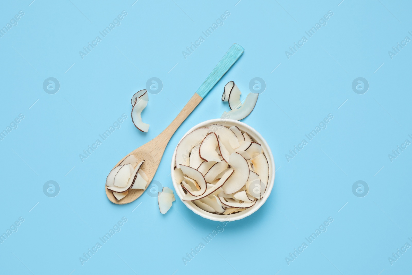 Photo of Flat lay composition with tasty coconut chips on light blue background