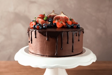 Photo of Fresh delicious homemade chocolate cake with berries on dessert stand against color background