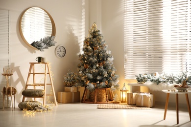 Beautiful decorated Christmas tree and gift boxes in festive room interior