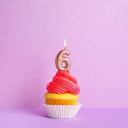 Birthday cupcake with number six candle on violet background