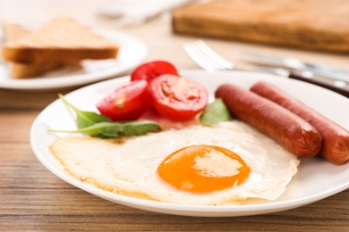 Tasty breakfast with fried egg on wooden table, closeup