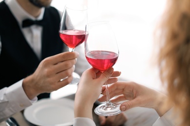 Photo of Young couple with glasses of delicious wine in restaurant