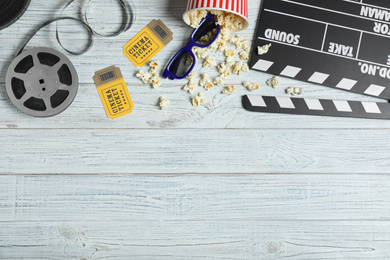 Photo of Flat lay composition with clapperboard, cinema tickets and 3d glasses on white wooden table, space for text