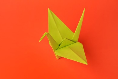 Origami art. Handmade paper crane on orange background