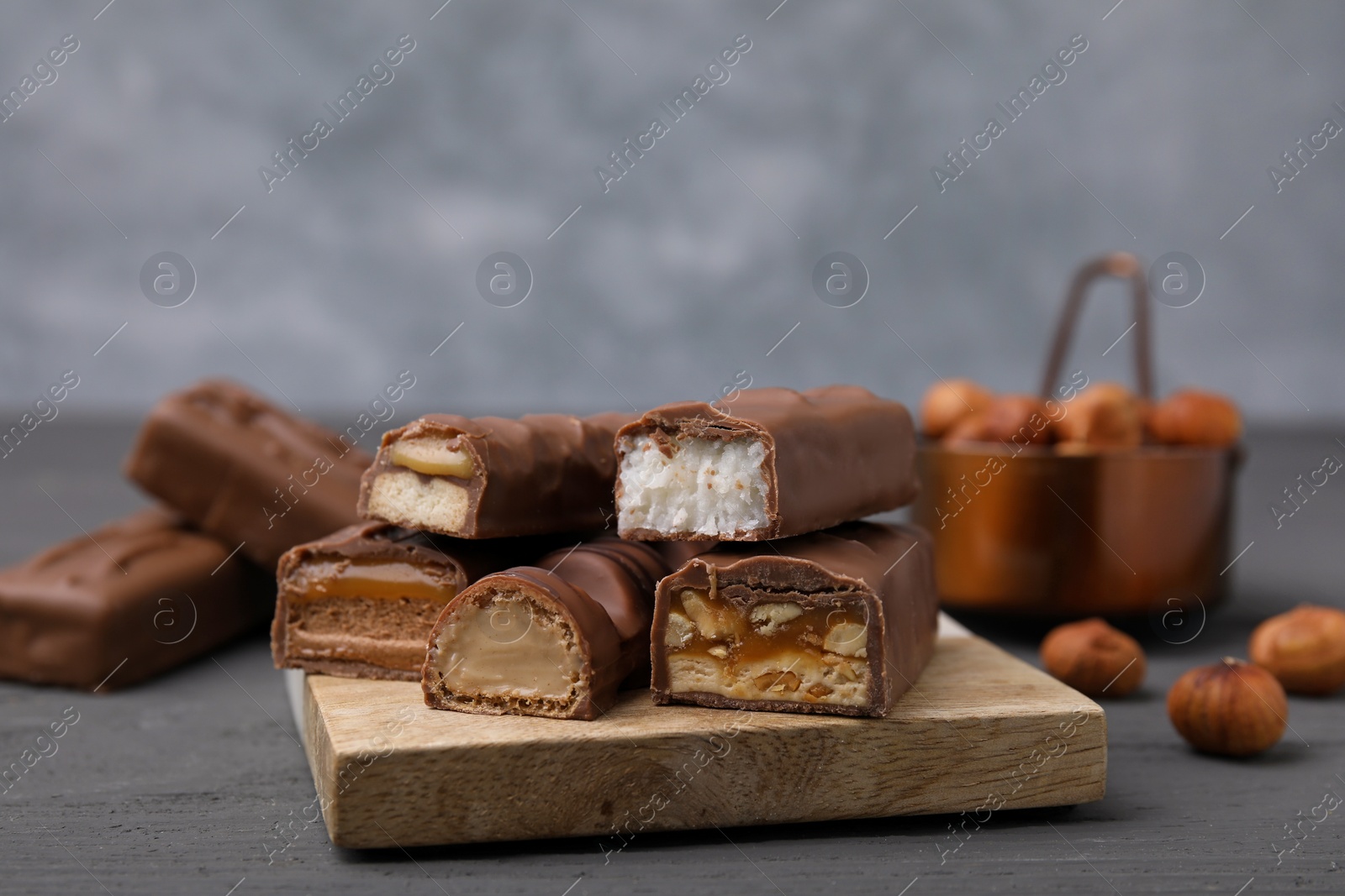 Photo of Pieces of different tasty chocolate bars on grey table, closeup