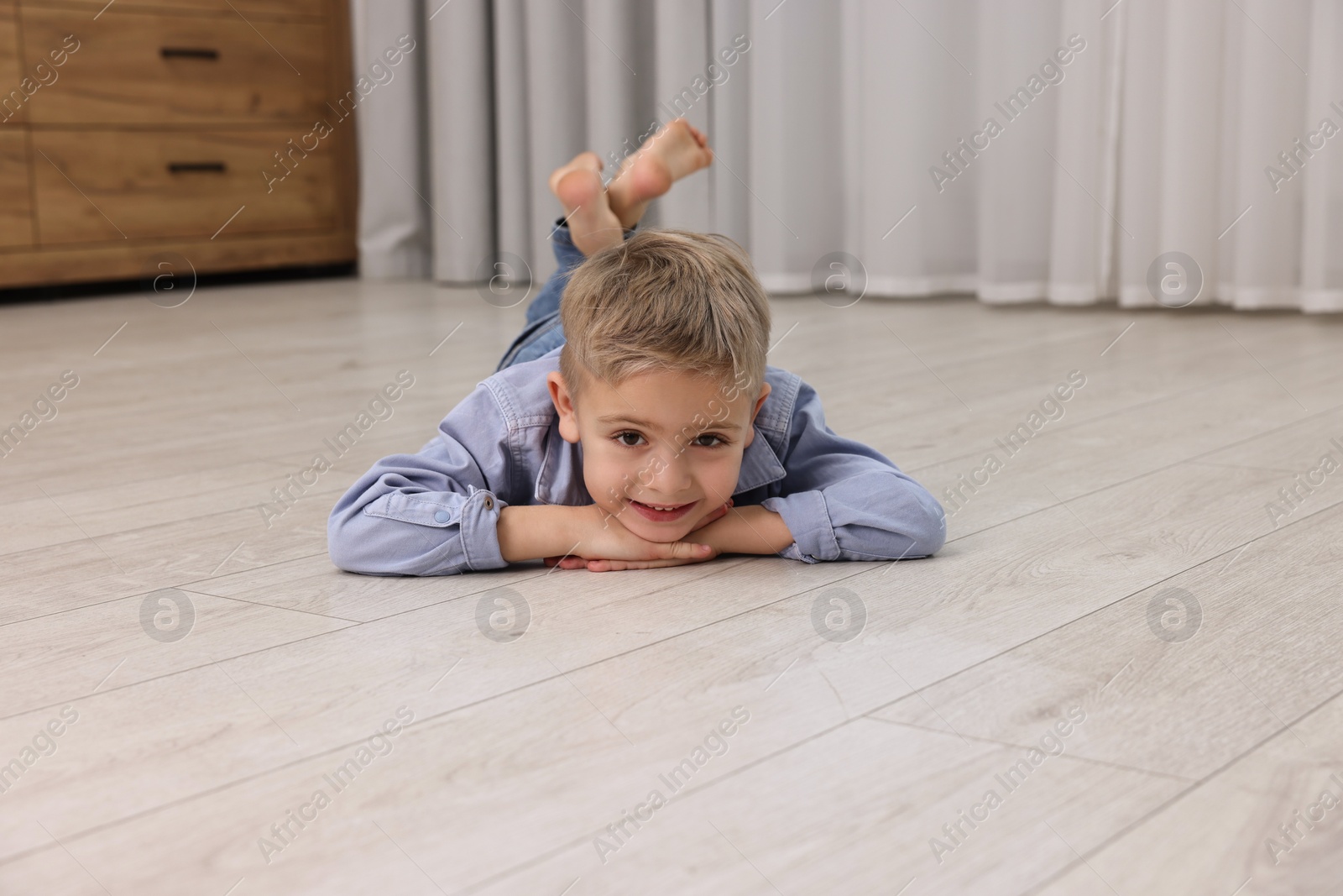 Photo of Cute little boy lying on warm floor at home. Heating system