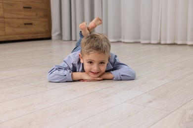 Cute little boy lying on warm floor at home. Heating system