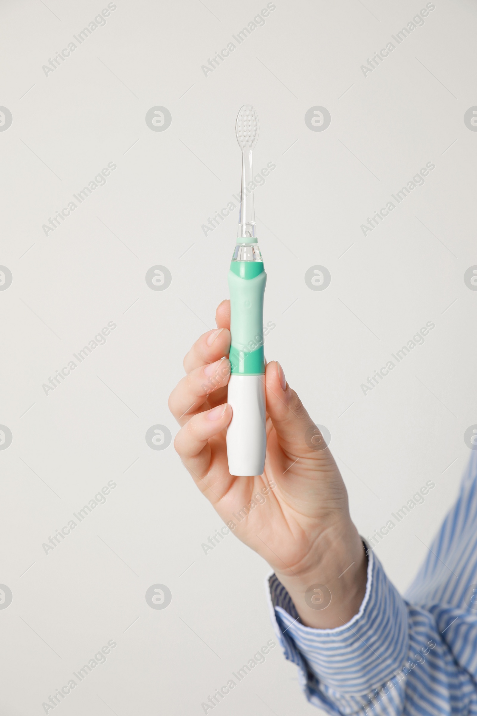 Photo of Woman holding electric toothbrush on white background, closeup