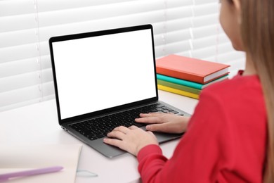 Photo of E-learning. Girl using laptop during online lesson at table indoors, closeup