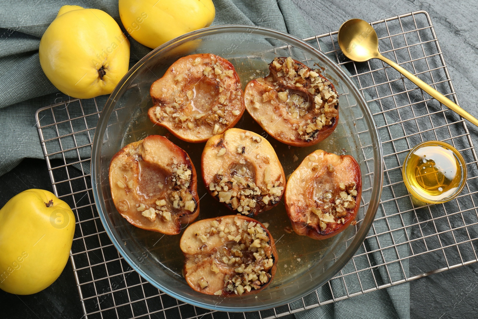 Photo of Tasty baked quinces with walnuts and honey in bowl on black table, flat lay