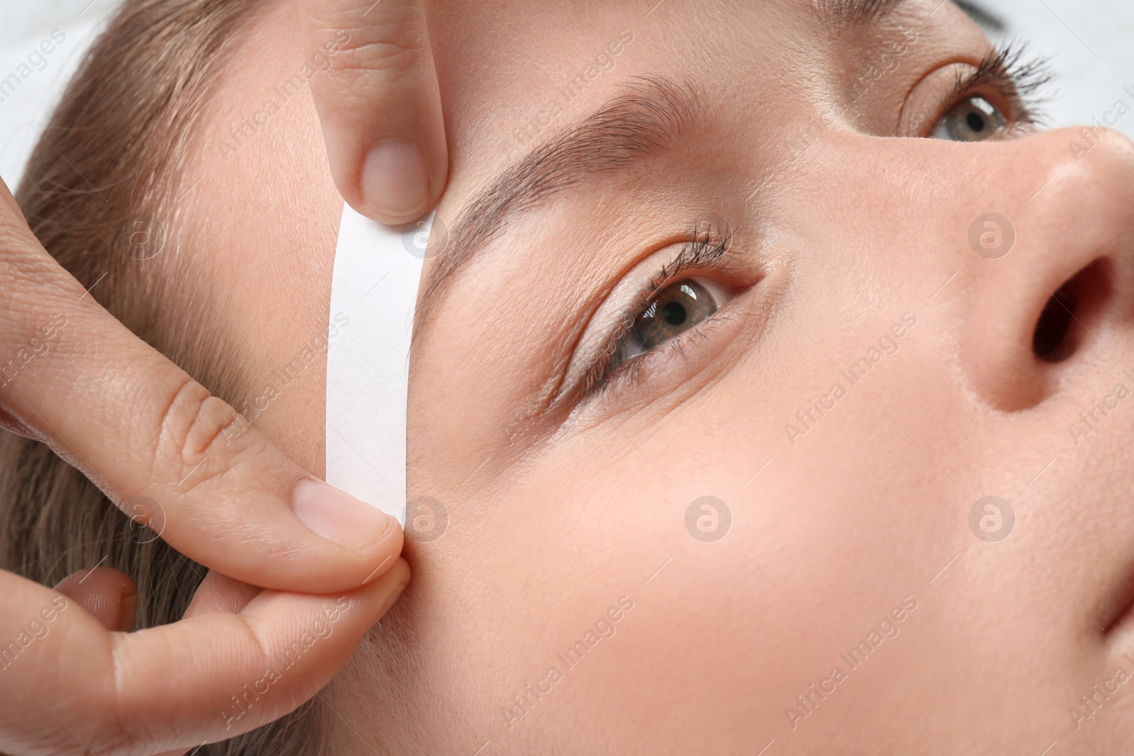 Photo of Young woman having eyebrow correction procedure in beauty salon, closeup