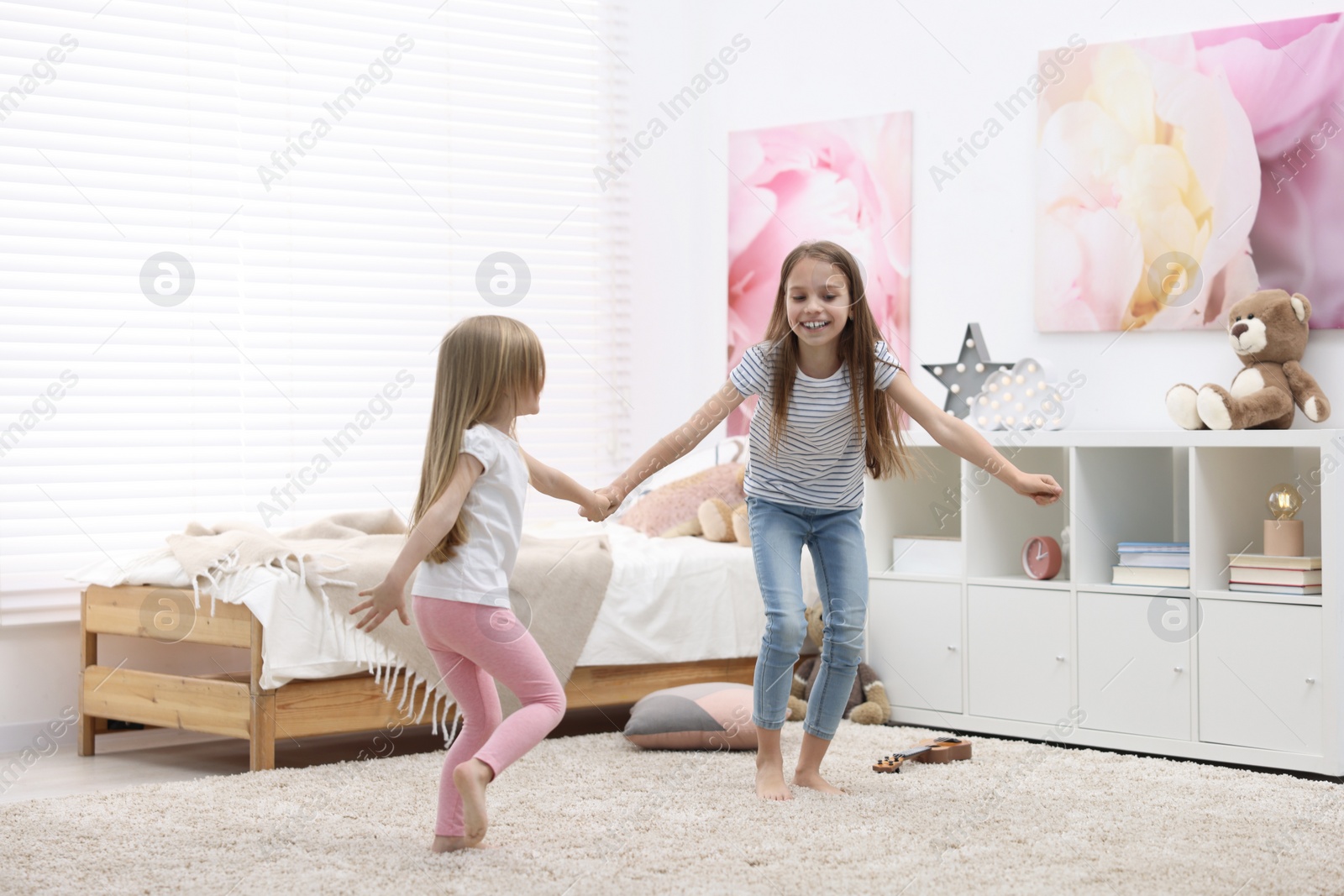 Photo of Cute little sisters having fun together at home