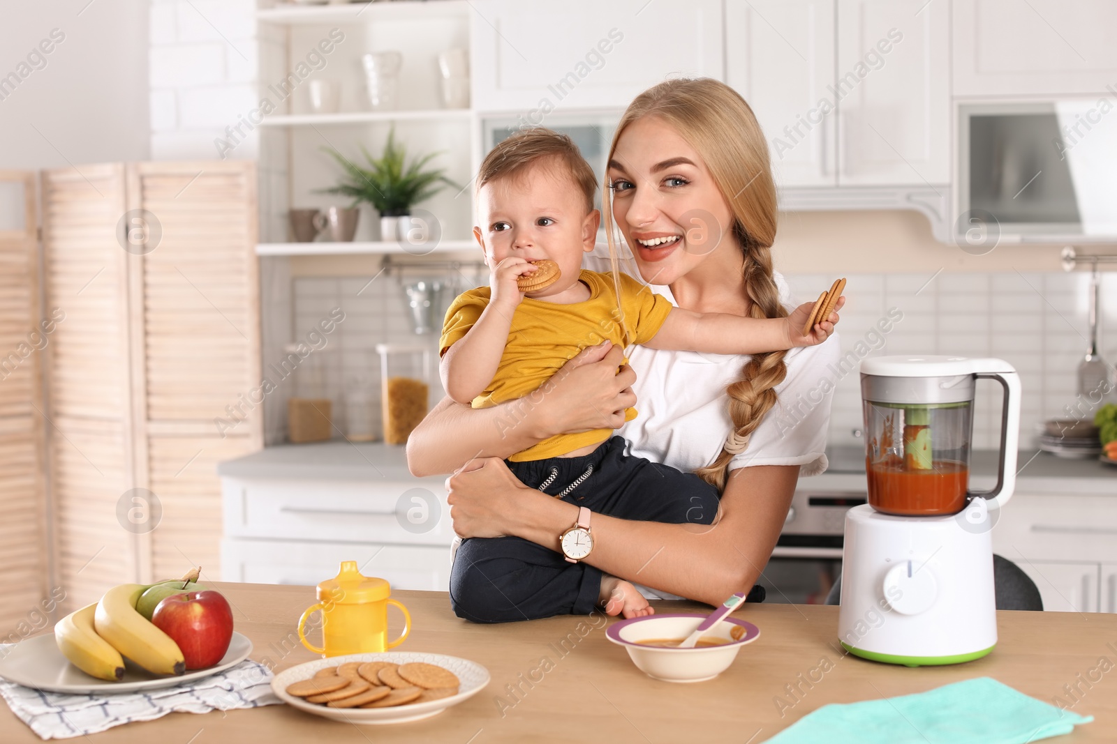 Photo of Woman feeding her child in kitchen. Healthy baby food