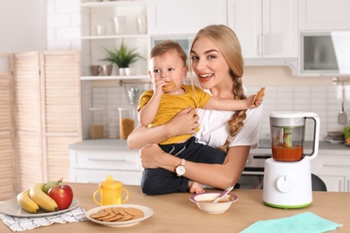 Woman feeding her child in kitchen. Healthy baby food