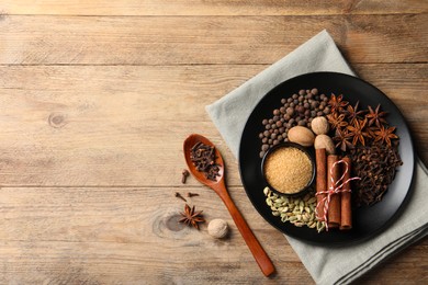 Photo of Dishware with different spices on wooden table, flat lay. Space for text