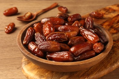 Tasty sweet dried dates in bowl on wooden table