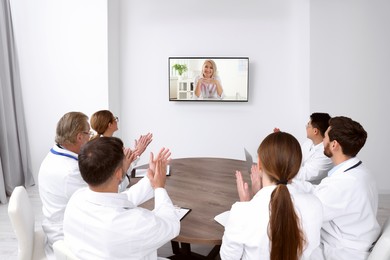 Image of Lecture with online participant. Doctors in meeting room. Using tv for videoconference