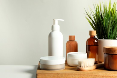 Photo of Different bath accessories and houseplant on white table against grey background, closeup. Space for text