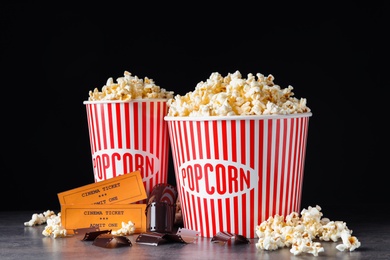 Photo of Popcorn, tickets and film footage on grey table against black background. Cinema snack