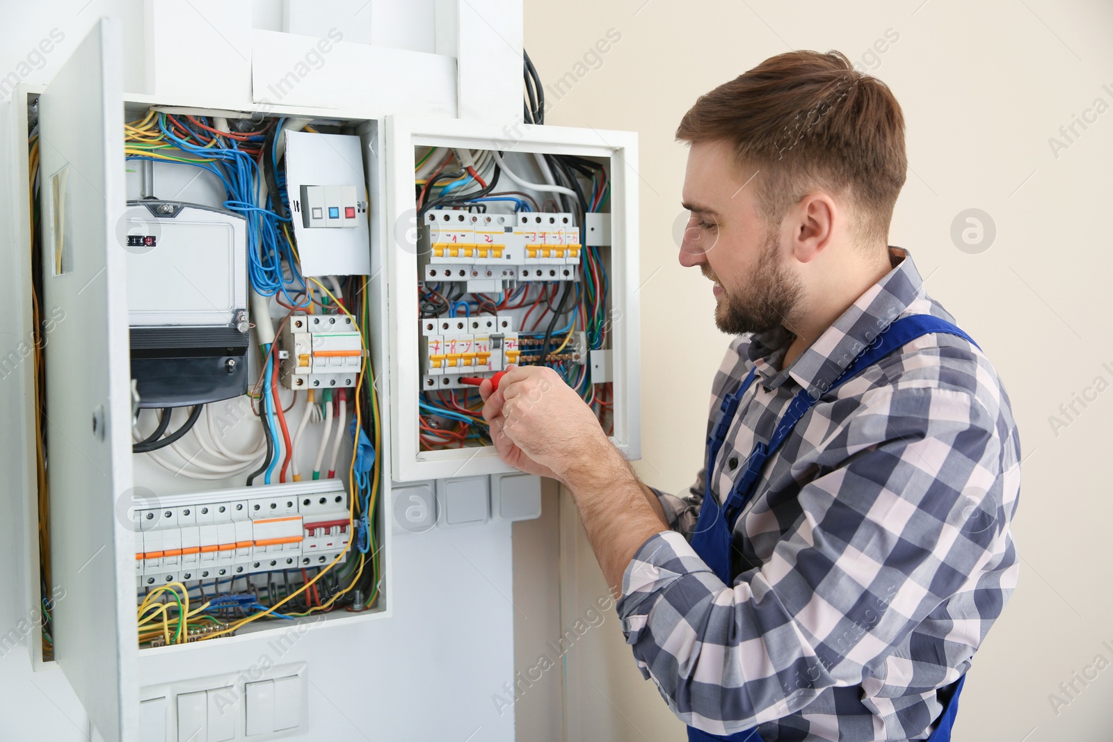 Photo of Electrician repairing fuse box with screwdriver indoors