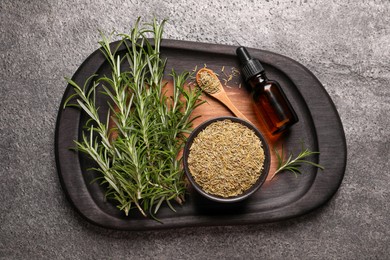 Bottle of essential oil, fresh and dry rosemary on grey table, top view