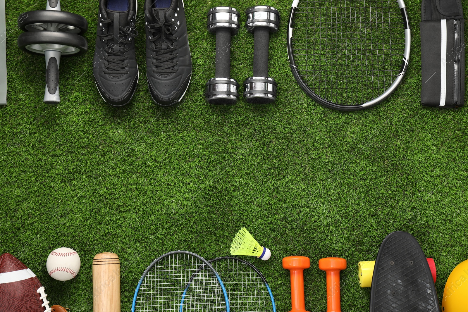 Photo of Different sports equipment on green grass, flat lay. Space for text