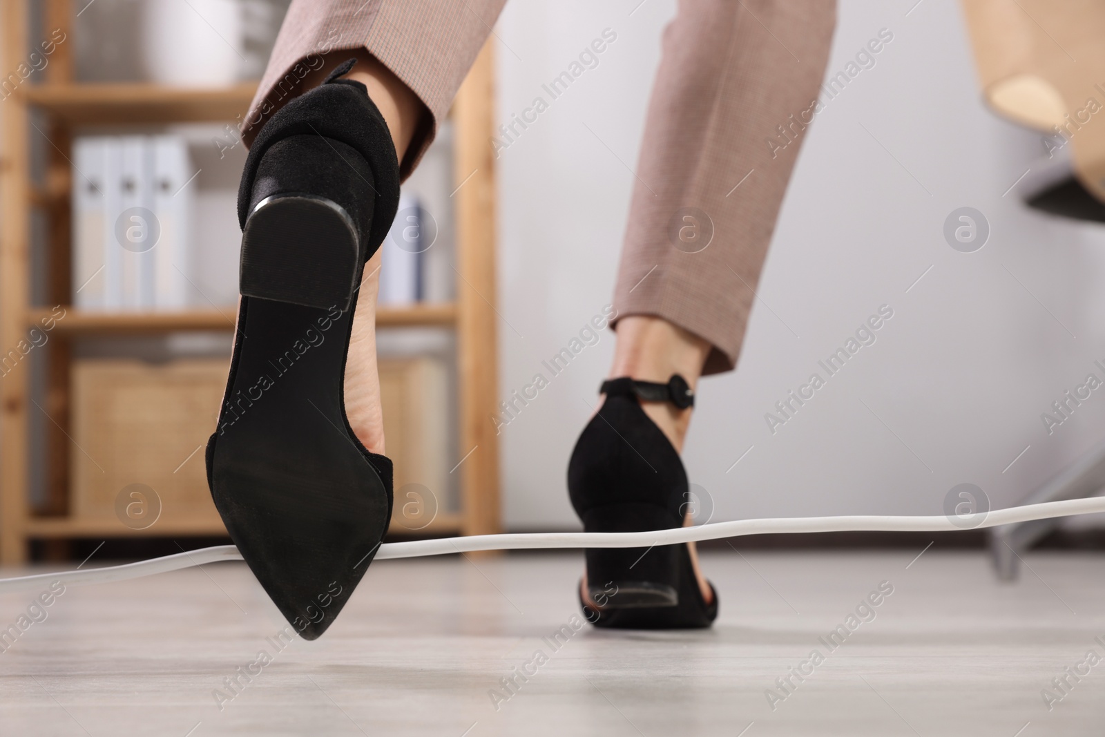 Photo of Woman tripping over cord in office, closeup