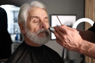 Photo of Professional barber trimming client's mustache in barbershop