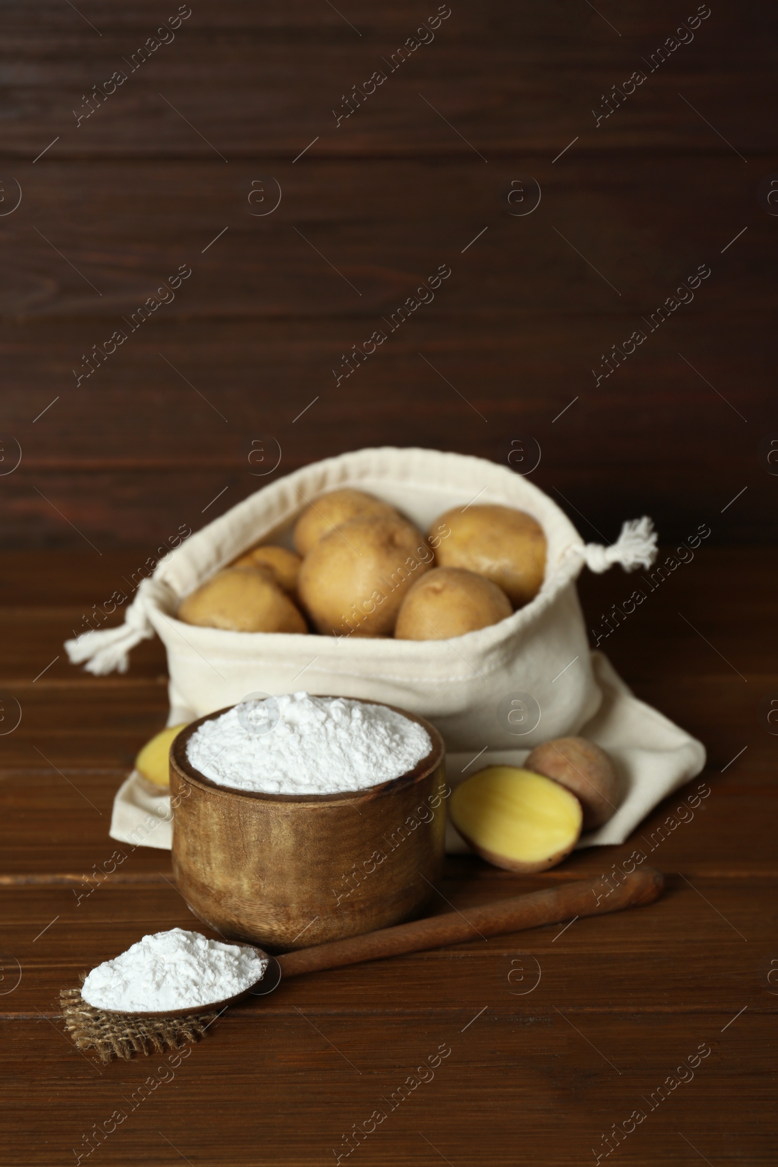 Photo of Starch and fresh raw potatoes on wooden table. Space for text