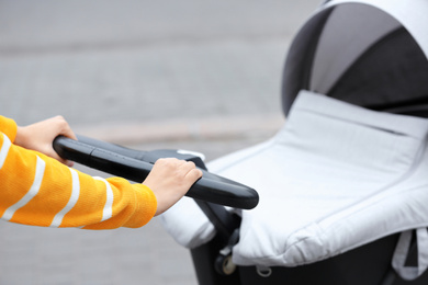 Photo of Nanny with baby in stroller walking on city street, closeup