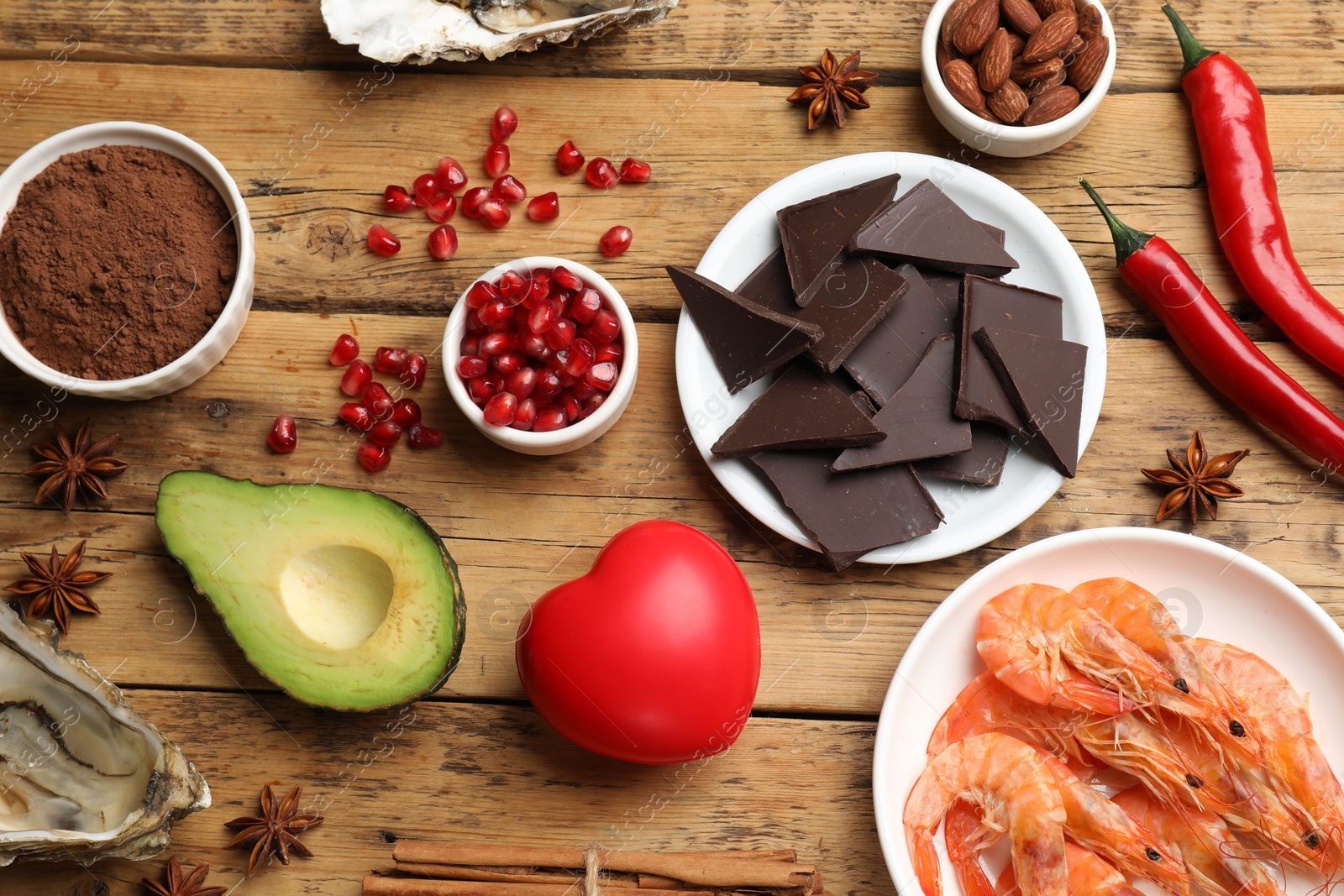 Photo of Natural aphrodisiac. Different food products and heart model on wooden table, flat lay