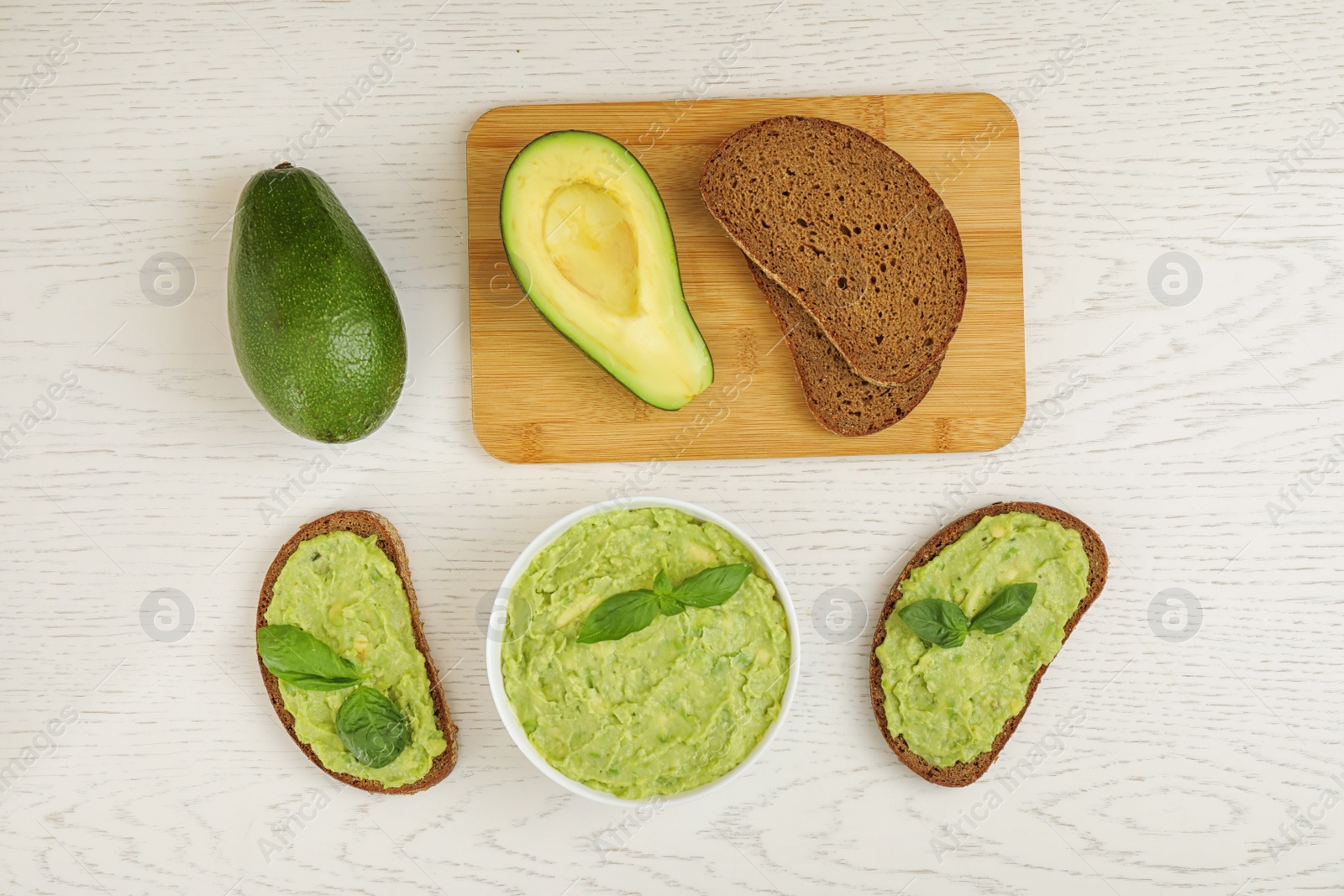 Photo of Flat lay composition with guacamole, sandwiches and avocados on white wooden table