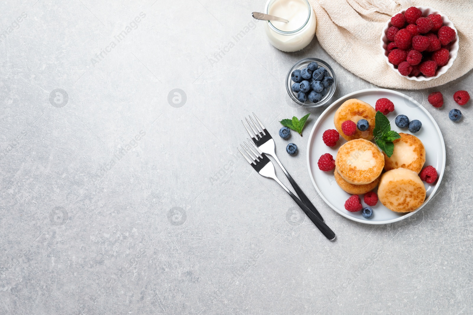 Photo of Delicious cottage cheese pancakes with berries on light table, flat lay. Space for text