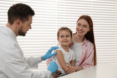 Children's hepatitis vaccination. Mother with her daughter in clinic. Doctor giving injection to little girl