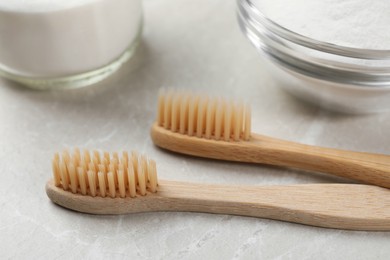 Photo of Bamboo toothbrushes and baking soda on light marble table