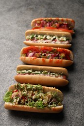 Photo of Delicious hot dogs with different toppings on grey table