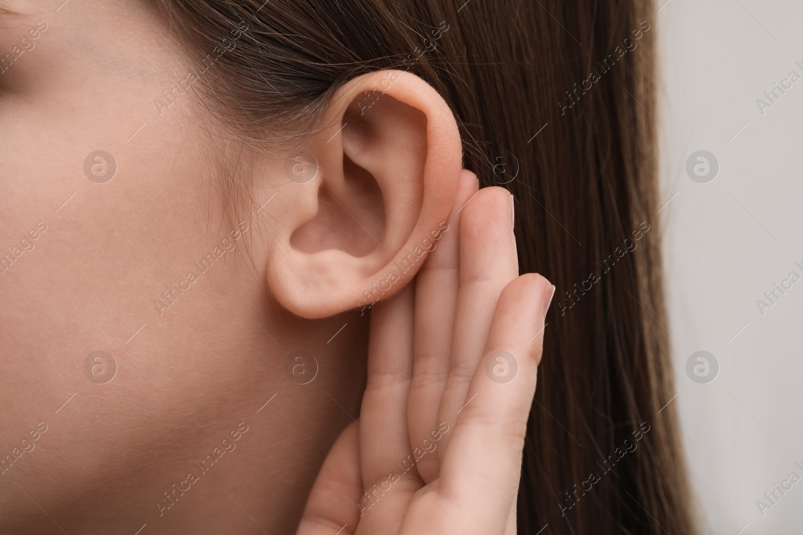 Photo of Little girl with hearing problem on grey background, closeup