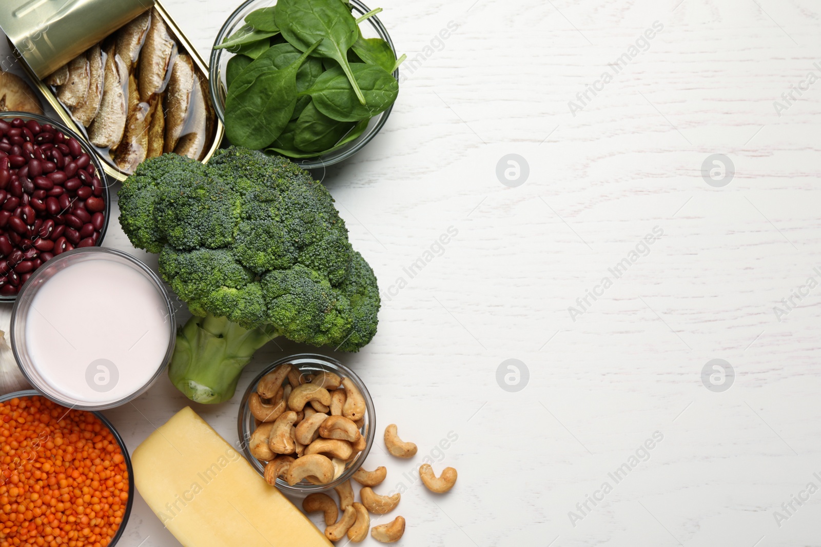 Photo of Set of natural food high in calcium on white wooden table, flat lay. Space for text