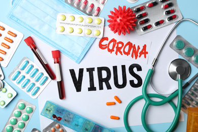 Photo of Flat lay composition with phrase CORONA VIRUS and medicines on light blue background