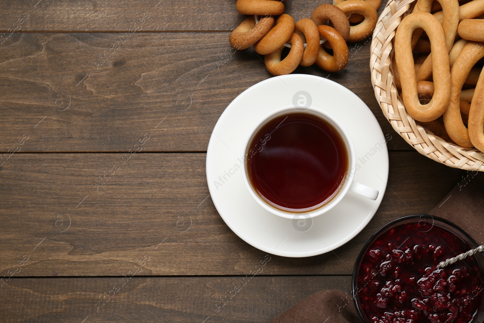 Photo of Flat lay composition with delicious ring shaped Sushki (dry bagels) and cup of tea on wooden table, space for text