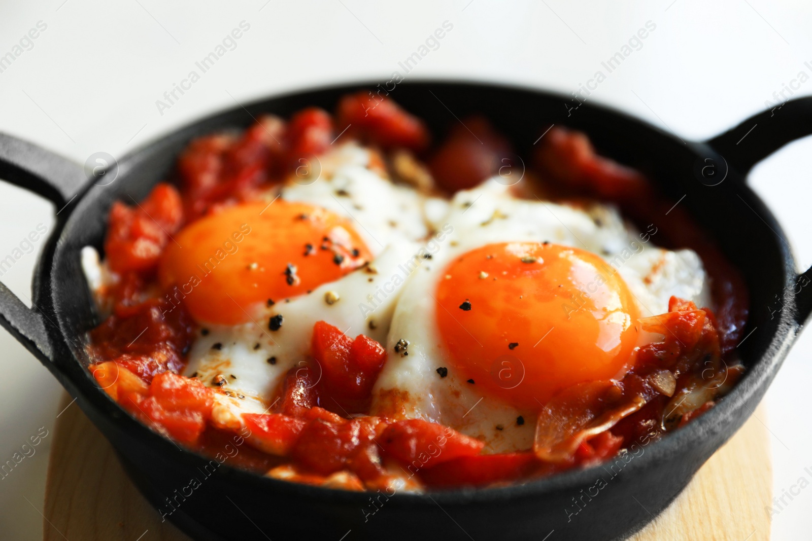 Photo of Tasty Shakshouka served in pan on white table, closeup