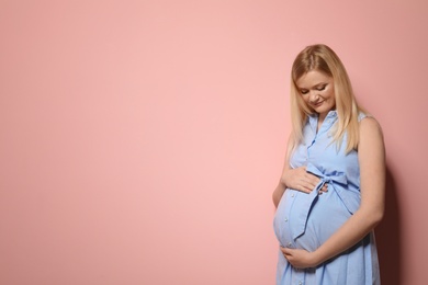 Beautiful pregnant woman in dress on color background. Space for text