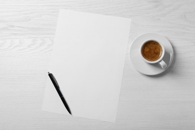 Blank paper sheet, pen and cup of coffee on white wooden table, flat lay. Space for text