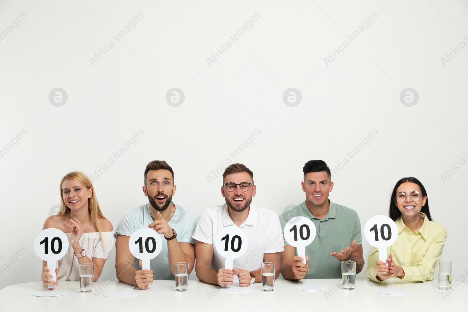 Photo of Panel of judges holding signs with highest score at table on white background