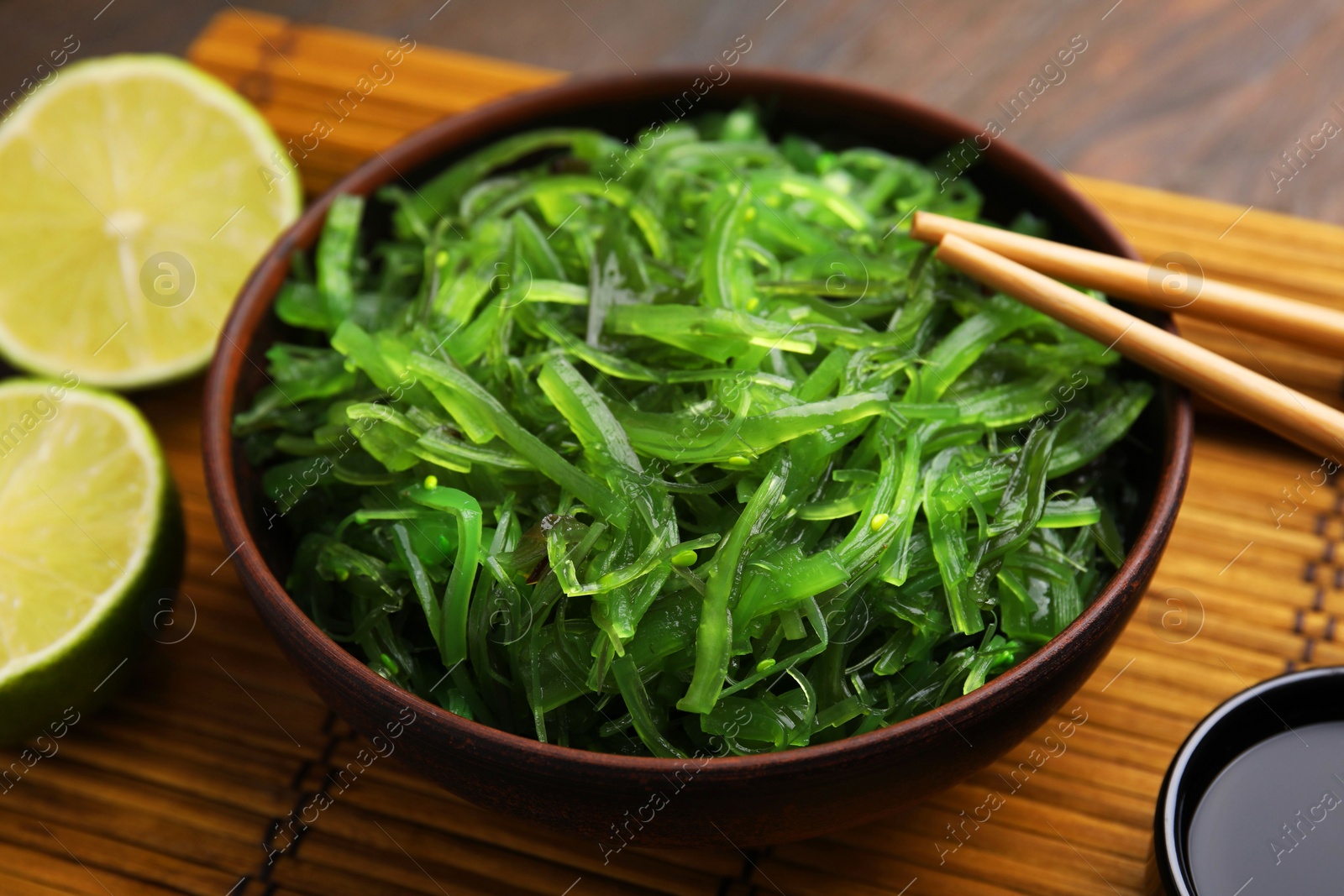 Photo of Tasty seaweed salad in bowl served on table, closeup