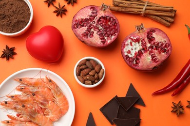 Photo of Natural aphrodisiac. Different products and heart model on orange background, flat lay