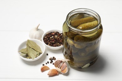 Photo of Tasty pickled cucumbers in jar and ingredients on white wooden table