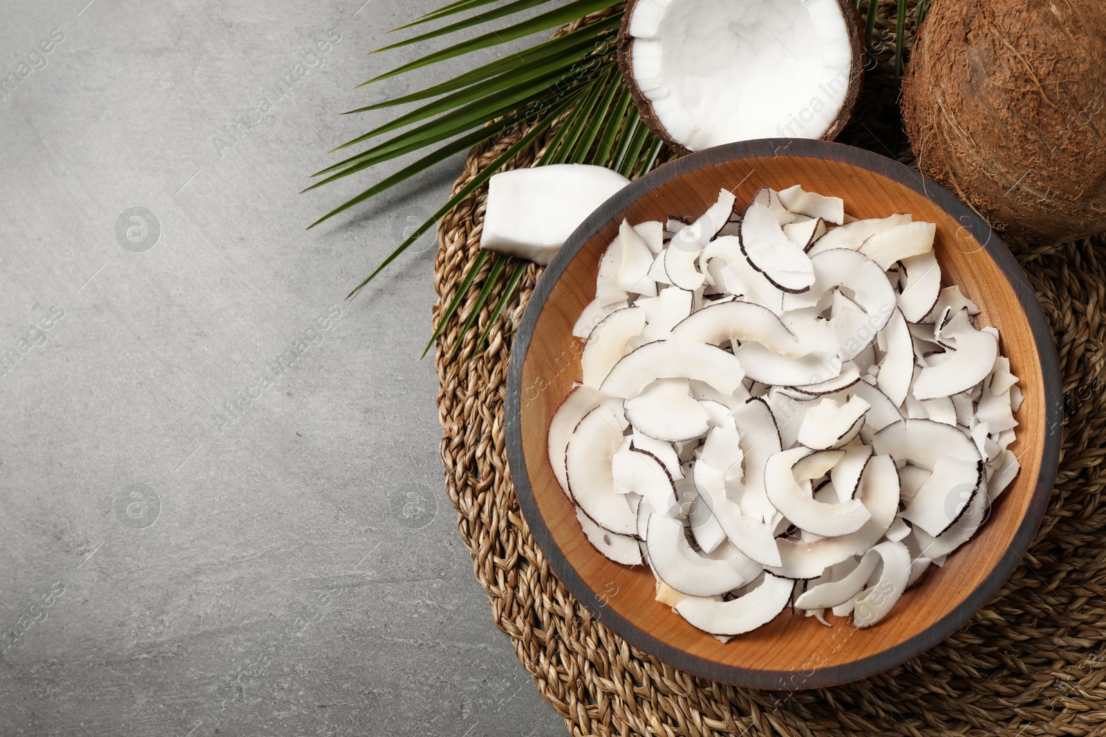 Photo of Flat lay composition with tasty coconut chips on grey table. Space for text